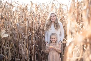 Two people stand together in a golden cornfield on a sunny autumn afternoon.