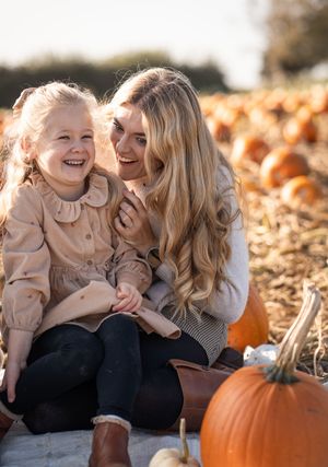 Candid autumn moments shared at a pumpkin patch with laughter and joy among fallen leaves.