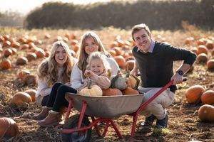 Candid moments of family fun and laughter while exploring a rustic pumpkin patch during golden hour.