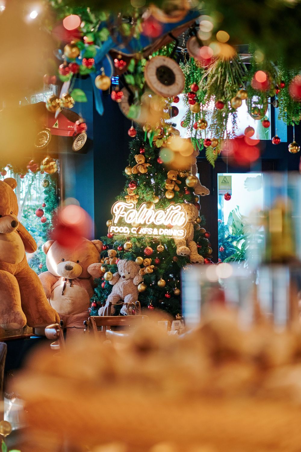 Festive bakery display with teddy bears, Christmas tree, and glowing Felnett neon sign decorations.