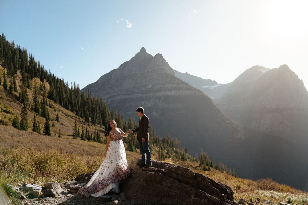 A couple celebrates their wedding day against a backdrop of majestic mountain peaks in Glacier National Park at Big Bend during golden hour.