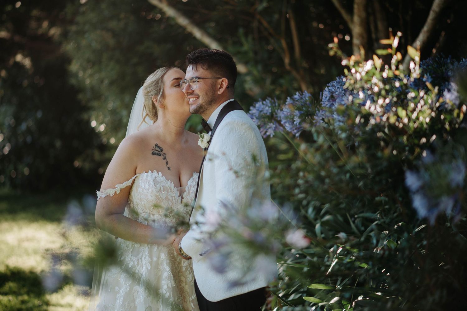 A couple in wedding attire embraces in a romantic outdoor garden setting during their special day.
