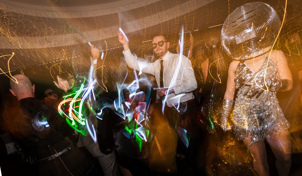 Dance party scene with colorful lights and silhouettes of people dancing in a dark venue.