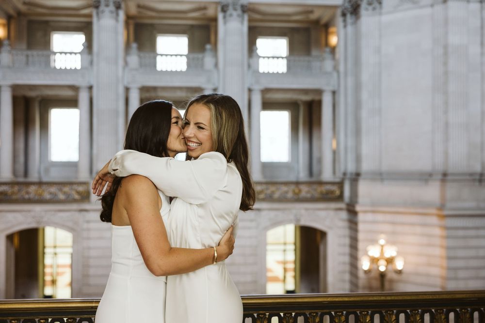 Intimate celebration in grand marble hall with classical columns and ornate details.