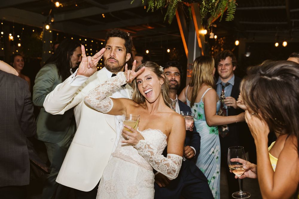 Wedding guests dancing and celebrating together on a dimly lit dance floor at an evening reception.