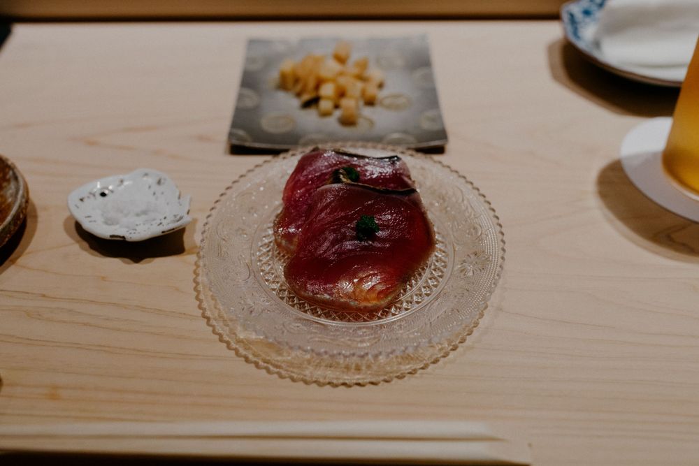 Fresh tuna sashimi with garnish served on ornate glass plate.