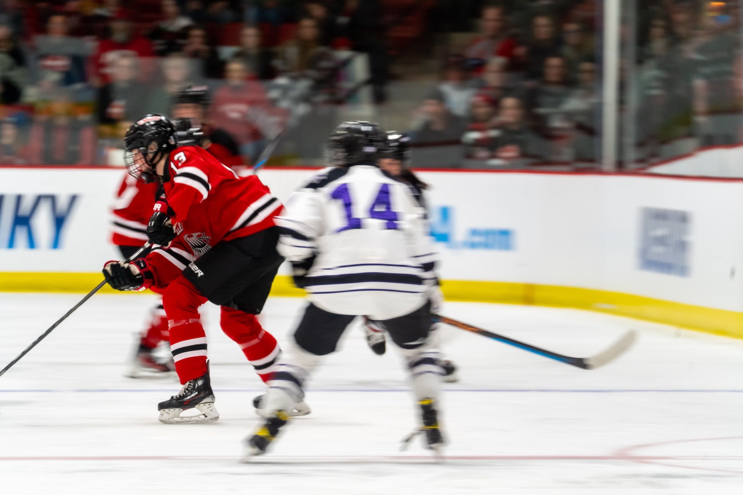 Motion-blurred action shot of hockey players from opposing teams during an intense game on the ice.