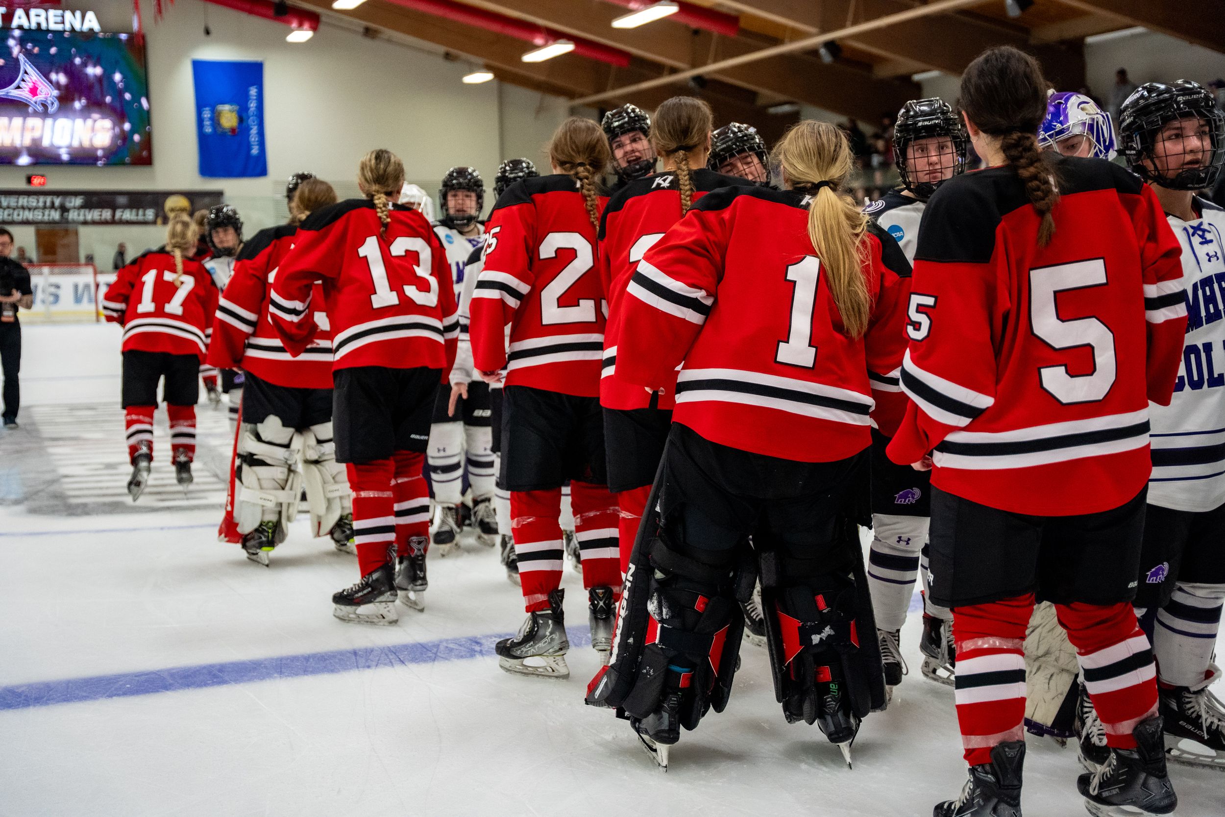 Hockey team in red and white striped jerseys lined up along boards during game at indoor ice arena.