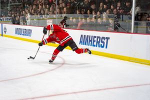 Hockey player in red uniform controls the puck during a game at Amherst's arena.