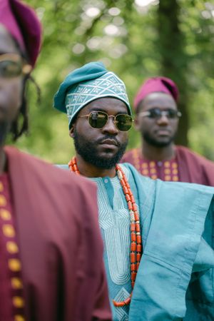 Close-up portrait showing detailed beadwork and traditional African headwear in turquoise and burgundy styling.