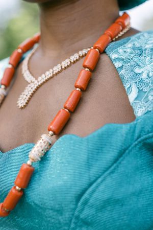 Close-up of coral and pearl beaded statement necklace against turquoise fabric.