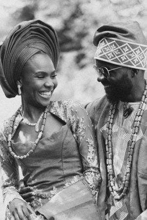 Black and white photo of a couple in traditional African dress sharing a candid moment together.