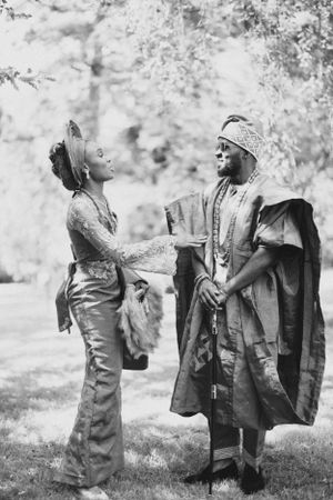 Black and white portrait of couple in traditional African formal wear having an animated conversation.