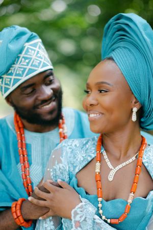 Close-up of couple in teal traditional outfits with coral beaded jewelry.