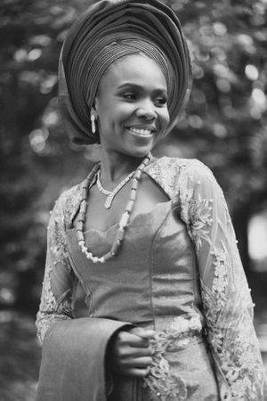 Beautiful black and white portrait of a woman in traditional African attire with gele headwrap and lace dress.