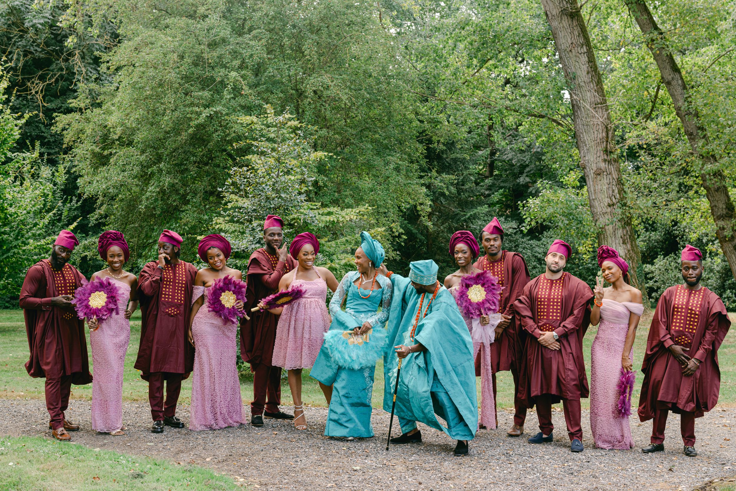 Festive wedding party in traditional African-inspired attire poses together outside.