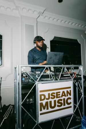 DJ booth setup with professional equipment and branded 'DJSEAN MUSIC' signage at event venue.