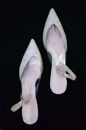Sparkly white pointy-toe slingback heels with rhinestone embellishments.