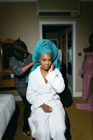 Getting ready scene with traditional headwrap and white robe in hotel room.