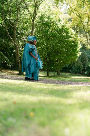 Long shot of turquoise traditional dress against lush green park background.