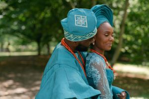 Side view of couple in coordinated turquoise traditional attire with ornate headwear.