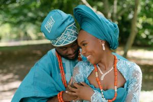 Traditional Nigerian attire in matching turquoise blue outfits featuring cultural beaded jewelry and headwear.