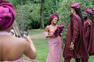 Wedding party in pink and burgundy attire posing for photos in a garden setting.