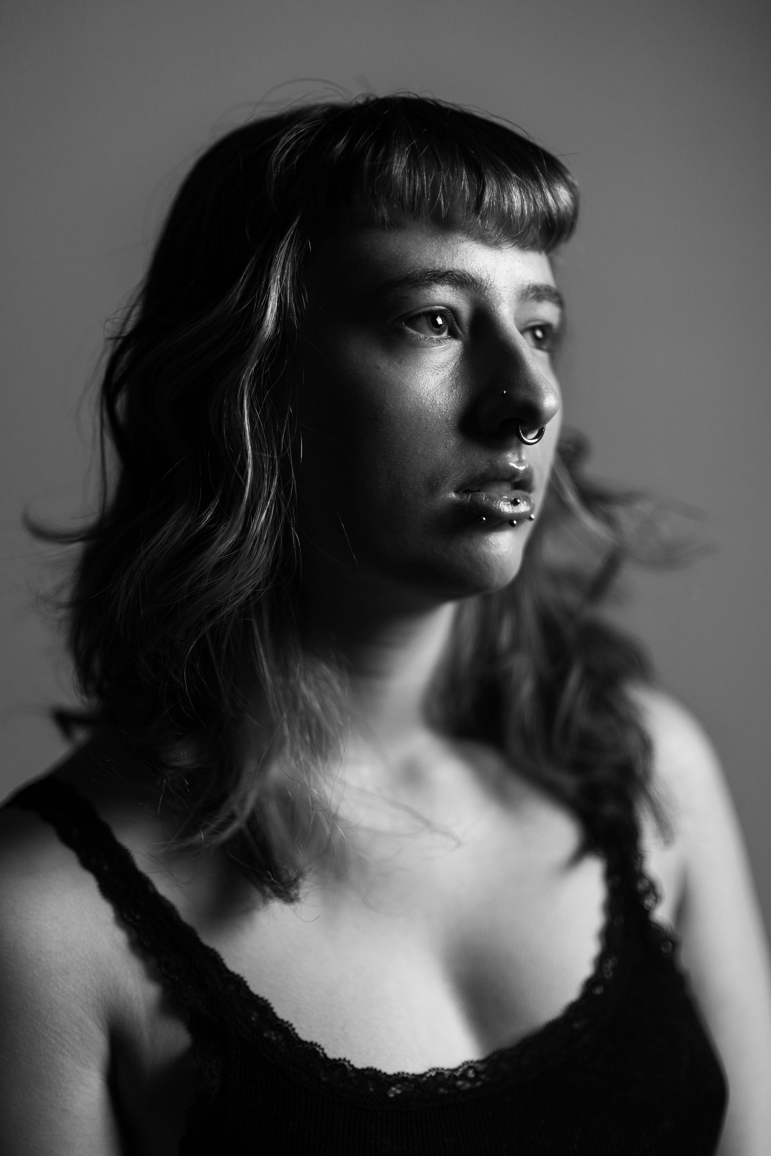 A dramatic black and white portrait series showing different angles of a person with bangs in moody lighting.
