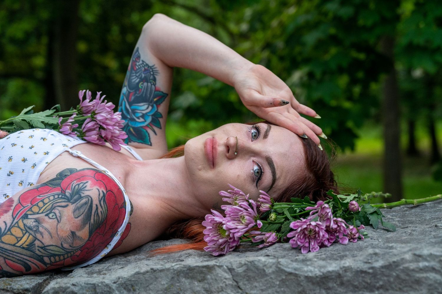 Artistic portraits with purple flowers on a stone surface in nature.