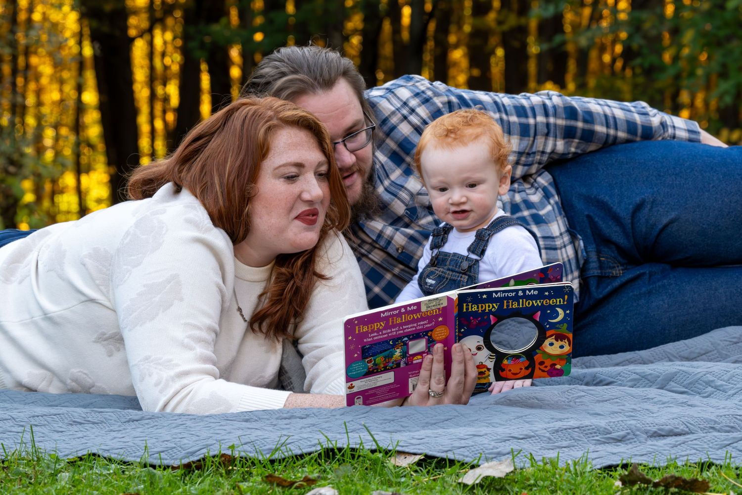 Family enjoying a relaxing autumn picnic on a blanket in a sunlit forest.
