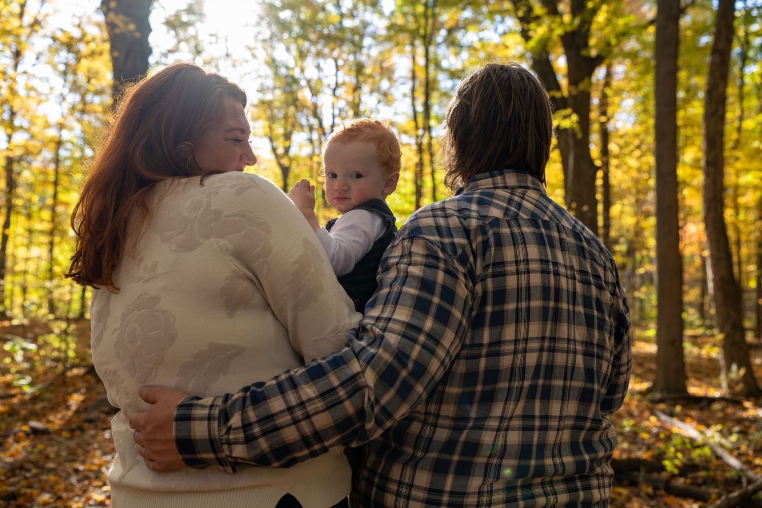 Cozy family moment captured on a blanket in golden autumn woods.
