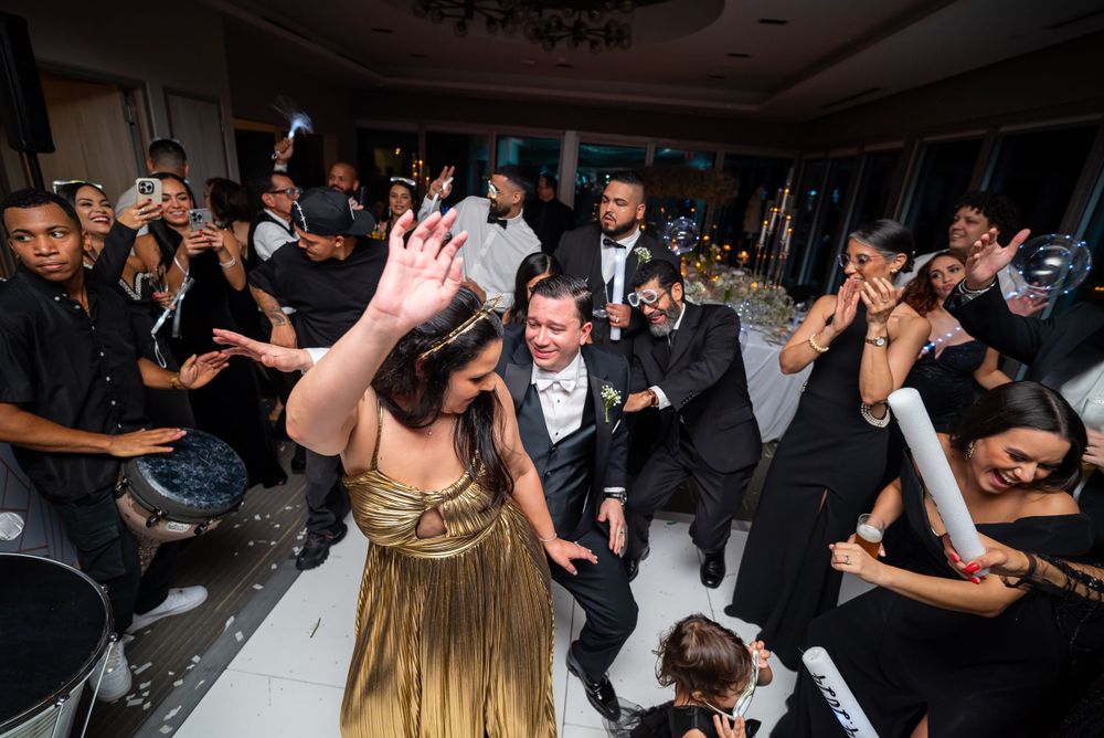 Festive wedding reception with guests dancing and celebrating on a crowded dance floor.