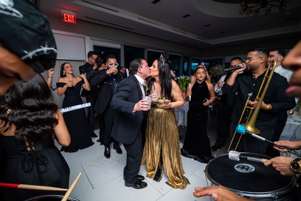 Wedding reception dance party with live band and guests celebrating in formal attire.