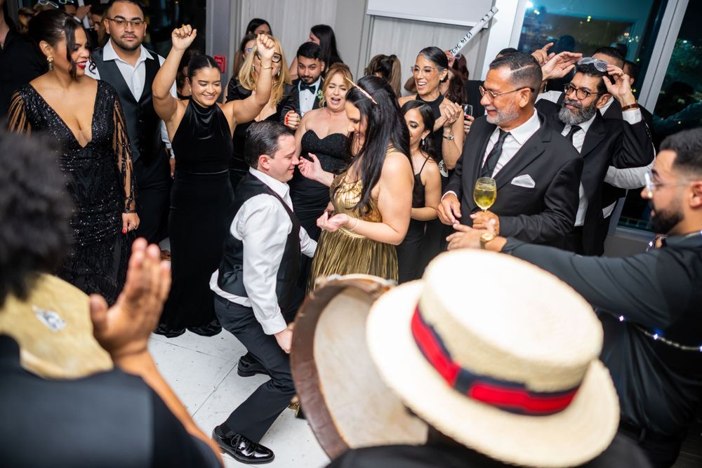 Wedding party dancing and celebrating with traditional tambourines and musicians at a lively reception.