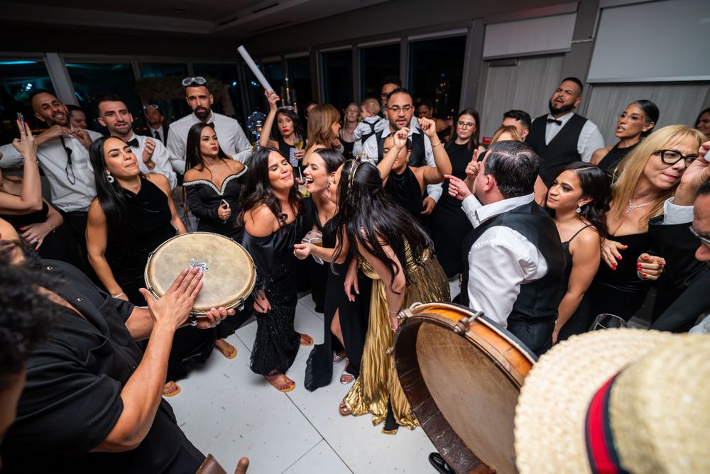 Festive dance circle forms as wedding guests celebrate with tambourines and music.