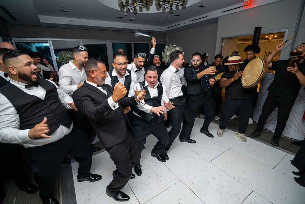Wedding party members dancing in synchronized formation at indoor reception venue.