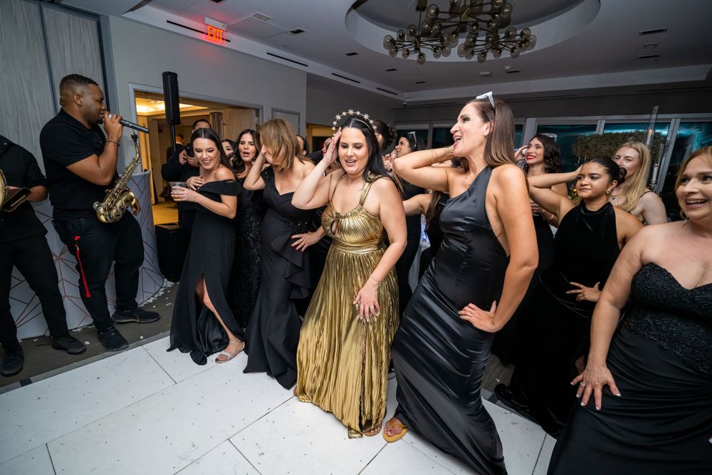 Wedding celebration with guests dancing and musicians performing in elegant ballroom setting.