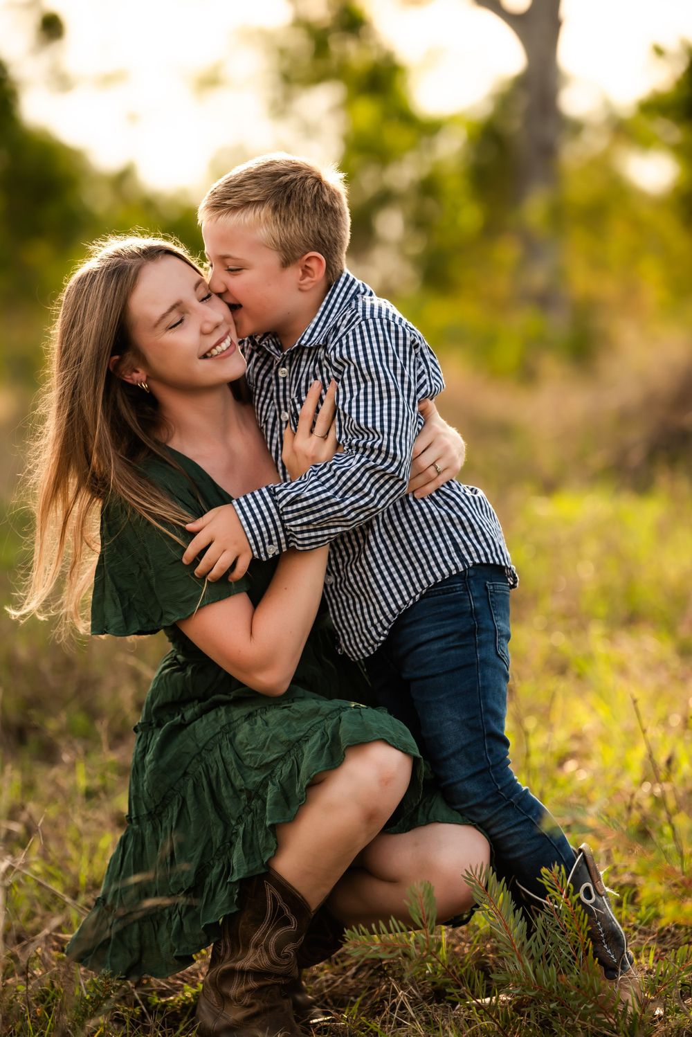 Heartwarming embrace captured in natural light with green dress and plaid shirt.