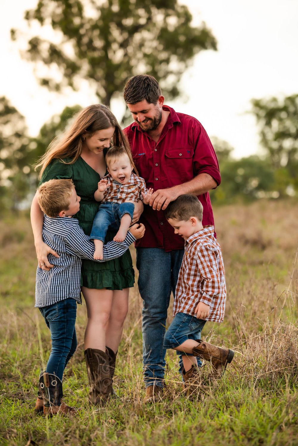 Happy family gathering close together in a sun-drenched field wearing coordinated casual outfits.