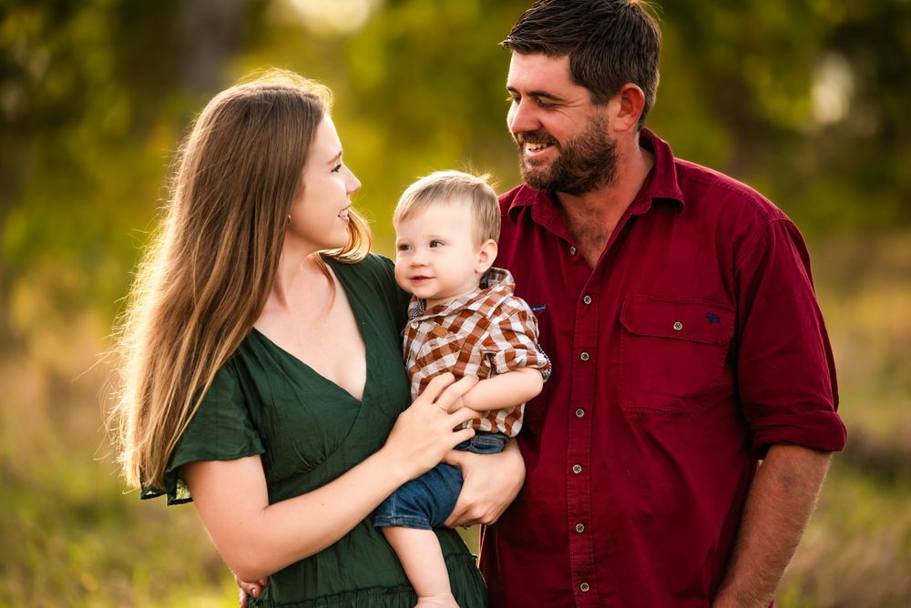Sweet outdoor family portrait with emerald dress and burgundy shirt at golden hour.