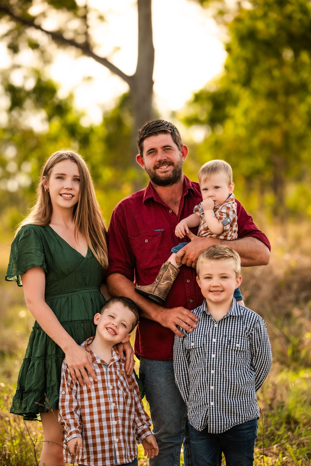 Outdoor family portrait at golden hour with everyone wearing coordinated casual attire.