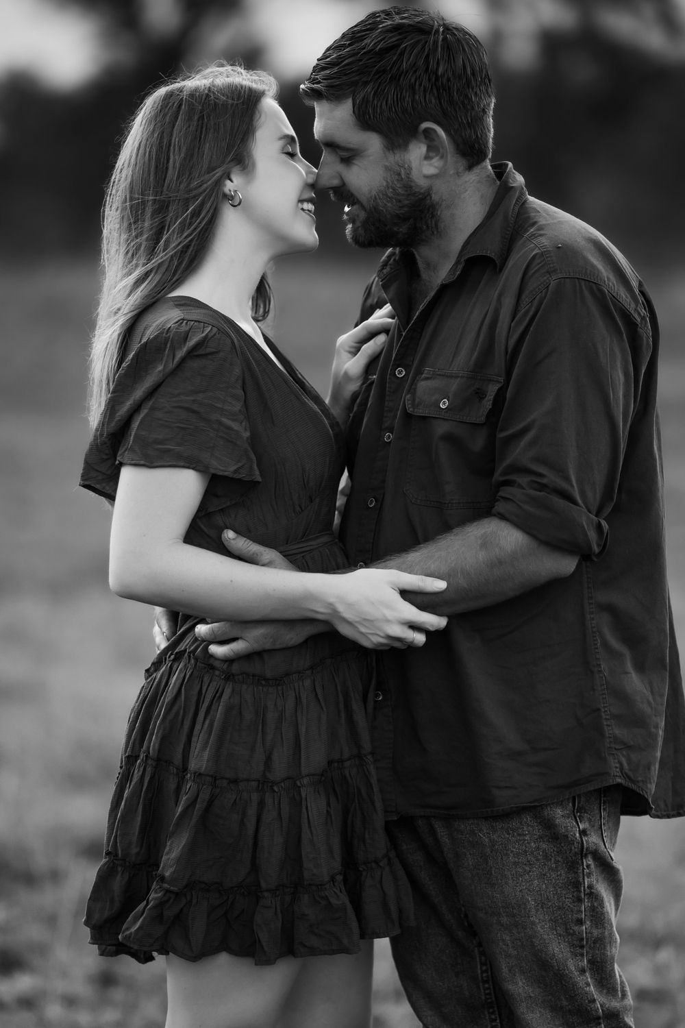 Intimate black and white portrait of a couple sharing a romantic moment outdoors.