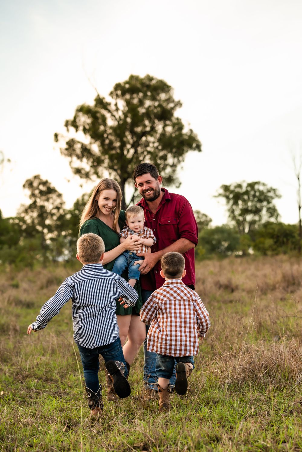 Family enjoying a candid moment together in a rural field at sunset.