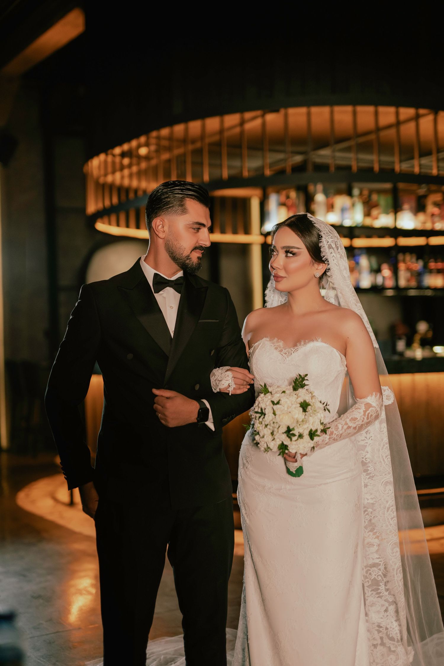 A romantic wedding moment captured in a dimly lit venue with elegant decor and warm lighting.