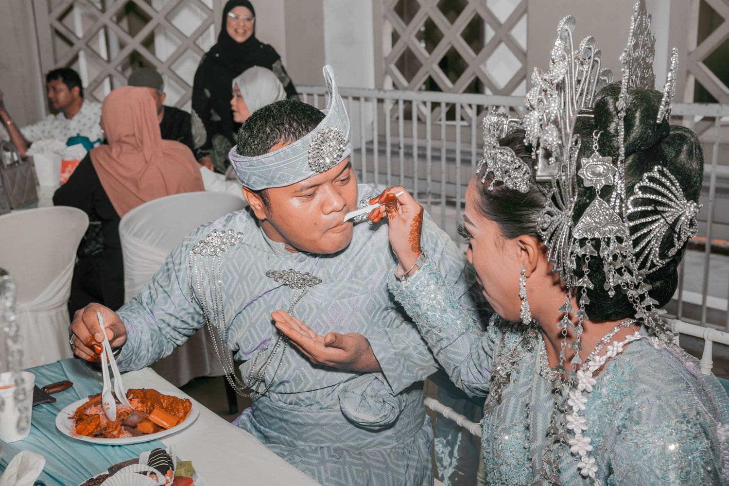 Wedding celebration moment showing guests enjoying food in festive decorated venue.