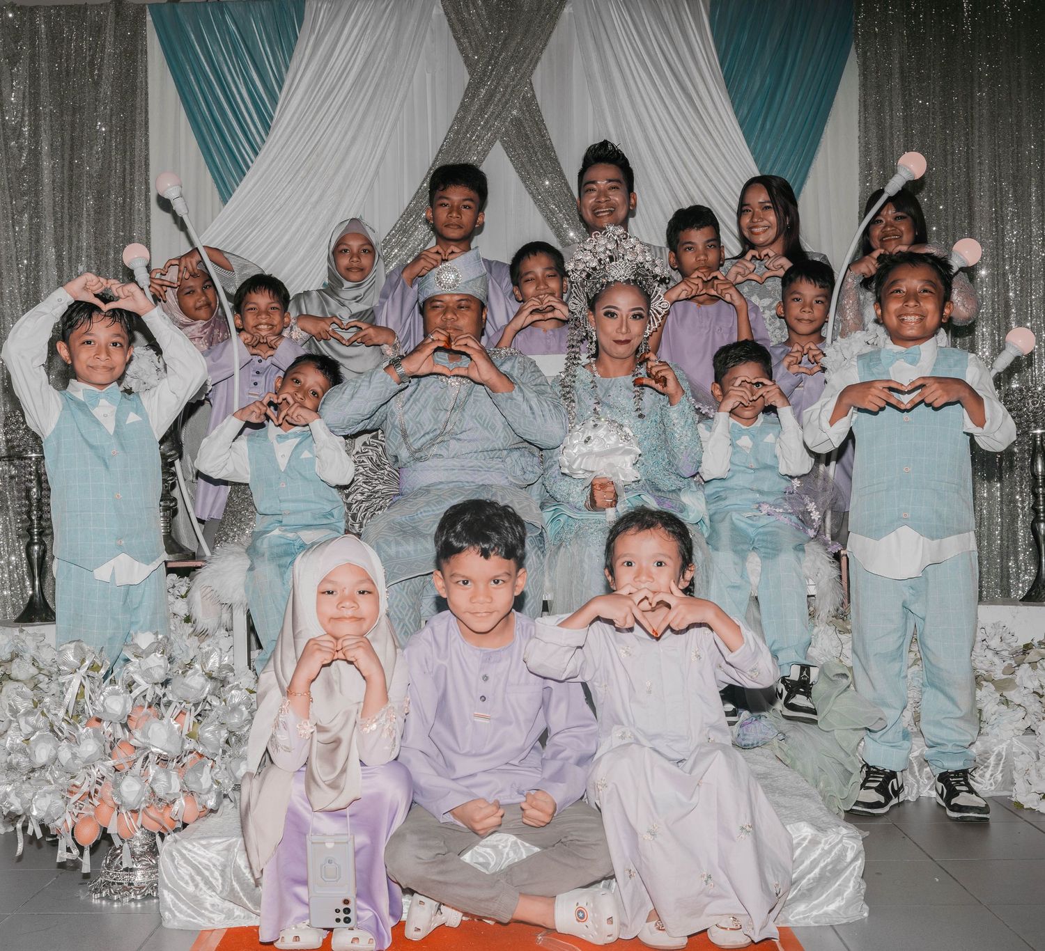 Group photo of children in matching outfits at a formal event with teal and white decorations.