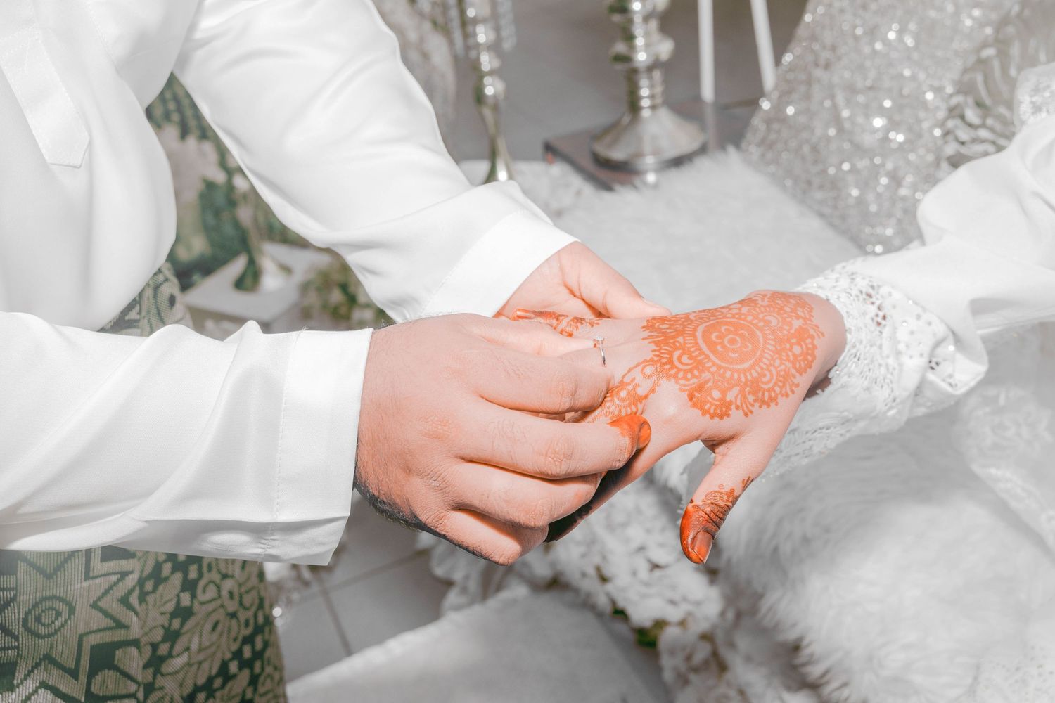 Close-up of hands during a traditional Malay wedding ritual with henna-decorated palms.