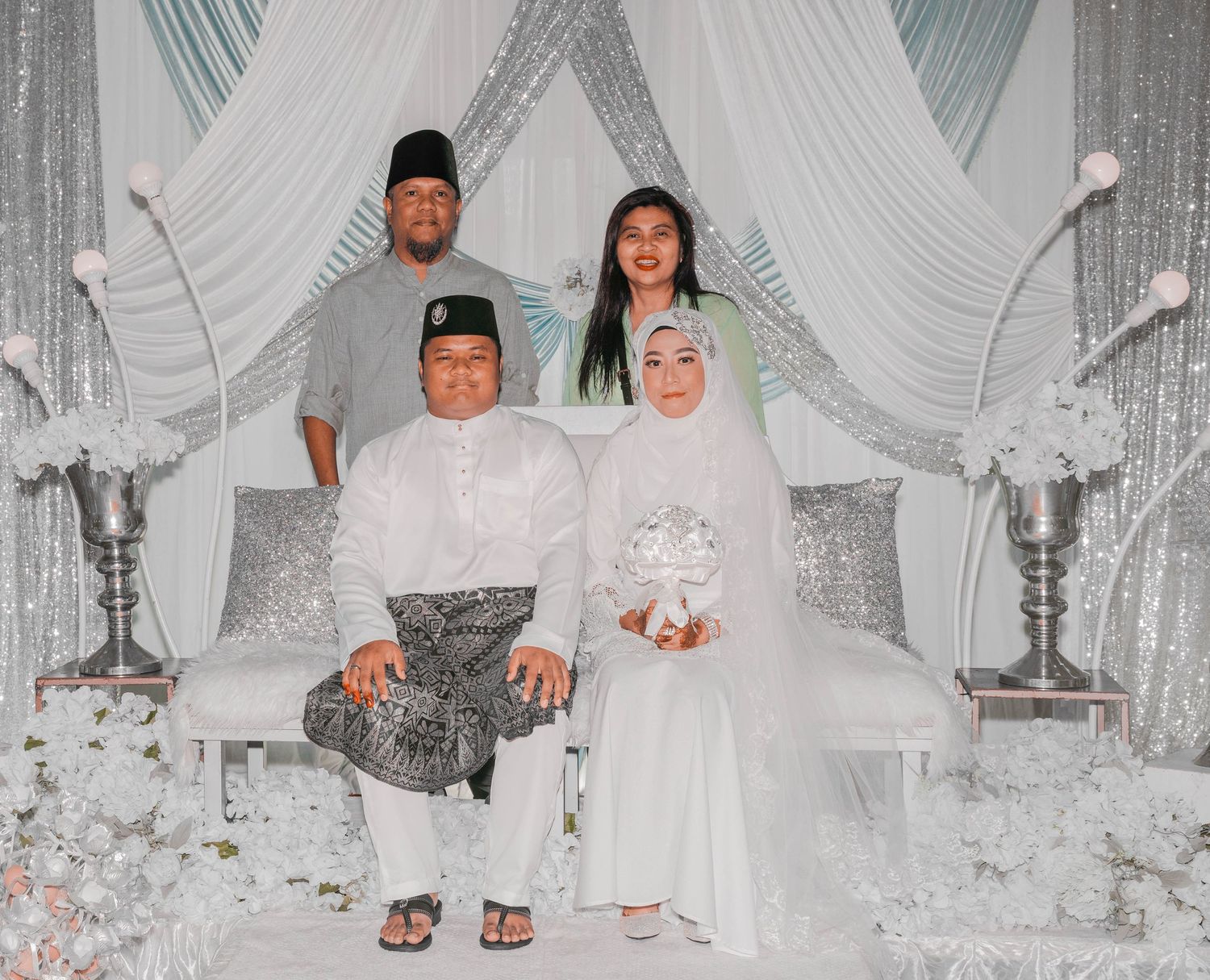 Wedding group photo in elegant white and silver themed decor with traditional elements.
