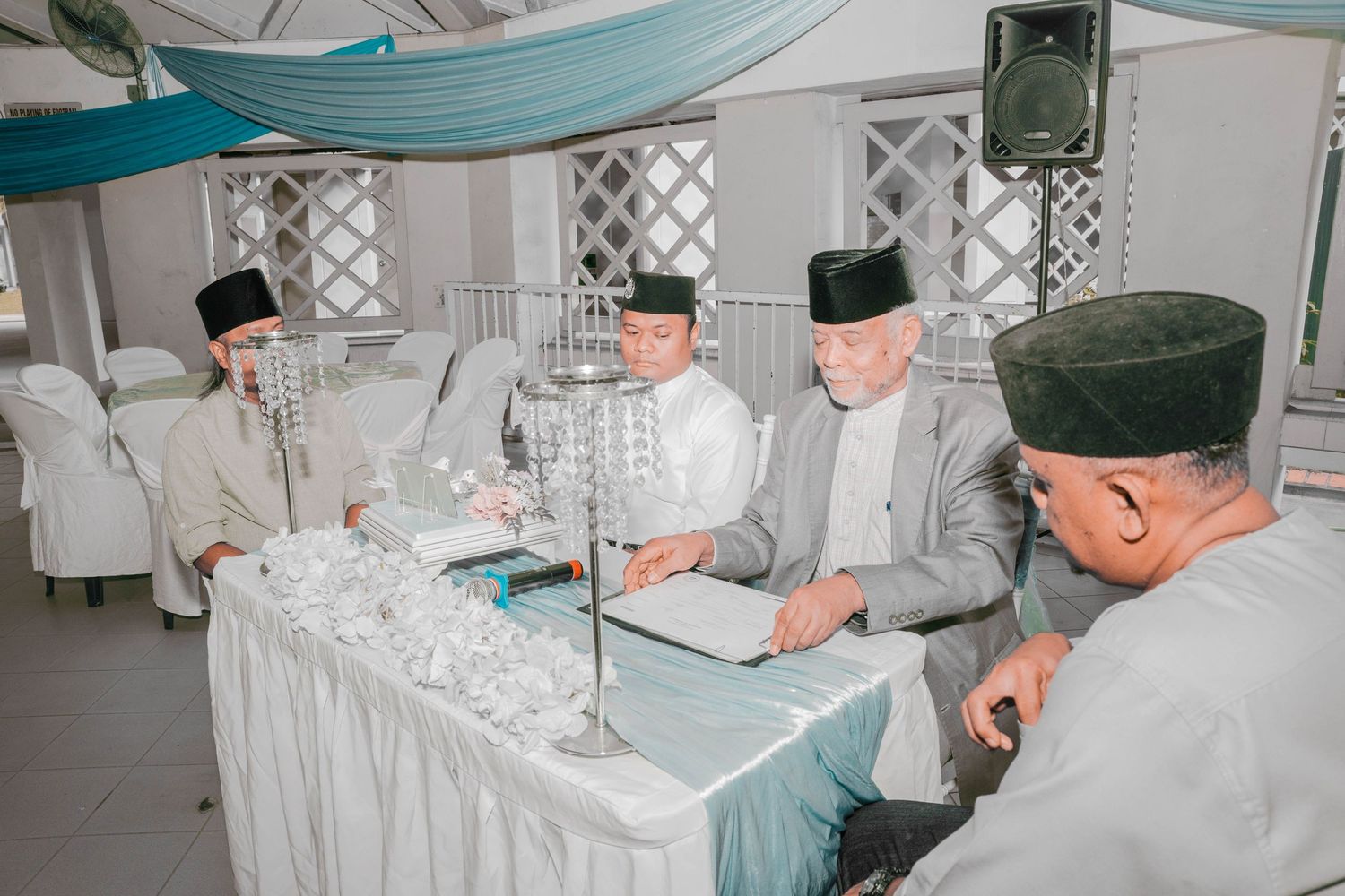 Religious officials in traditional attire seated at a table during a ceremony.