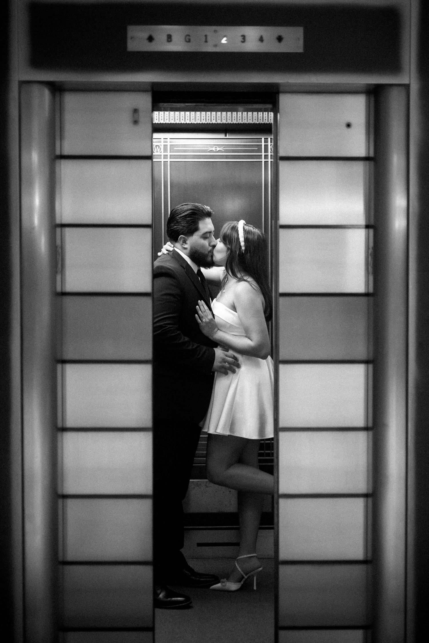A romantic black and white photograph of a couple sharing an intimate moment in an elevator.